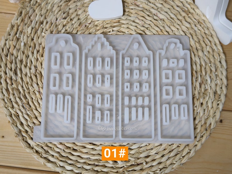 May include: A silicone mold with four separate sections, each shaped like a house with multiple windows. The mold is white and has a smooth surface. The text "01#" is printed on the bottom of the mold.