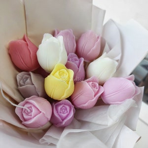 May include: A bouquet of handmade soap flowers in the shape of tulips. The bouquet includes pink, purple, white, and yellow soap flowers.