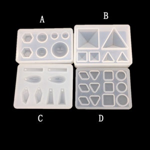 Puede incluir: Cuatro moldes de silicona para fundición de resina, etiquetados como A, B, C y D. El molde A tiene formas redondas y geométricas. El molde B tiene formas cuadradas, rectangulares y triangulares. El molde C tiene formas largas y delgadas. El molde D tiene formas redondas, cuadradas y triangulares.