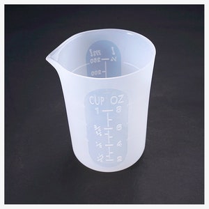 May include: A translucent white measuring cup with a pouring spout. The cup has markings for cups and ounces, with measurements from 2 ounces to 8 ounces. The cup is made of a flexible material and is suitable for kitchen use.