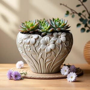 Puede incluir: Una maceta de cerámica en forma de corazón, de color crema, con diseños florales en relieve, llena de suculentas verdes. La maceta está sobre una superficie de madera, con pequeñas flores moradas y blancas esparcidas.