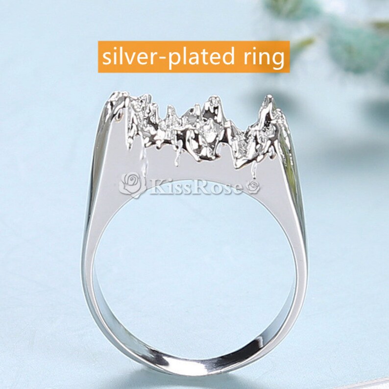 May include: Silver-plated ring with a textured, mountain-like design. The ring is a statement piece with a unique and modern style.