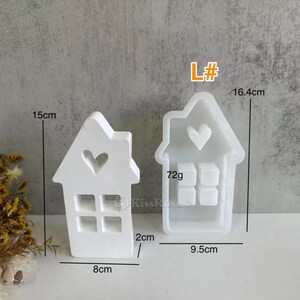May include: Two white silicone molds shaped like houses with heart and window cutouts. The larger mold measures 9.5 cm wide, 16.4 cm tall, and weighs 72 grams. The smaller mold measures 8 cm wide and 15 cm tall.