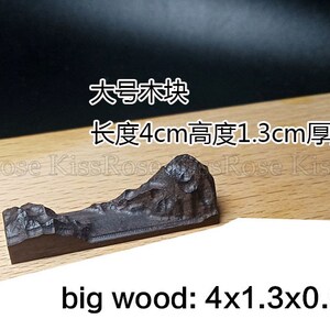 May include: A dark brown wooden mountain sculpture. The sculpture is 4 inches long, 1.3 inches high, and 0.9 inches thick. The text "big wood: 4x1.3x0.9cm" is written below the sculpture.