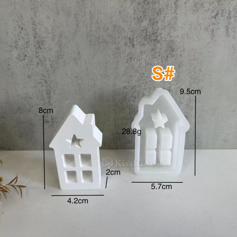 Może przedstawiać: Biała plastikowa forma do odlewania w kształcie domu z wycięciem w kształcie gwiazdy. Forma ma 9,5 cm wysokości, 5,7 cm szerokości i 4,2 cm głębokości. Forma waży 28,8 grama. S#