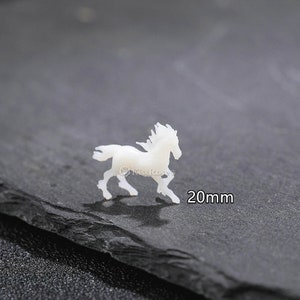 Op de afbeelding: Witte porseleinen paardenfiguur, 20 mm groot.