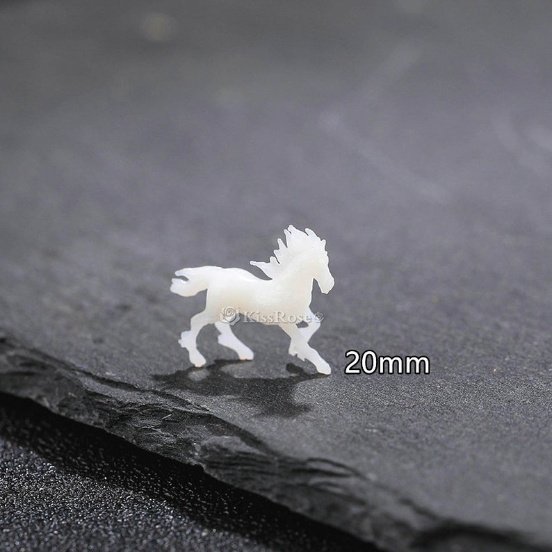 Op de afbeelding: Witte porseleinen paardenfiguur, 20 mm groot.