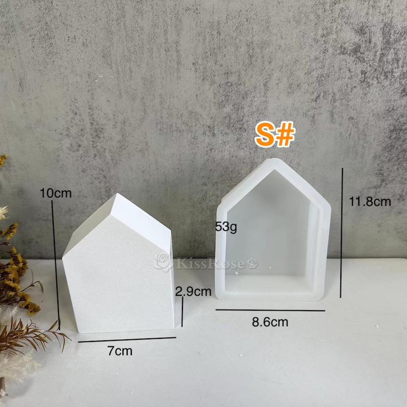 K&ouml;nnte beinhalten: Wei&szlig;e Silikonform in Form eines Hauses mit Ma&szlig;en in Zentimetern. Die Form ist 11,8 cm hoch, 8,6 cm breit und 2,9 cm tief. Die Form wiegt 53 Gramm. S# ist auf der Form geschrieben.