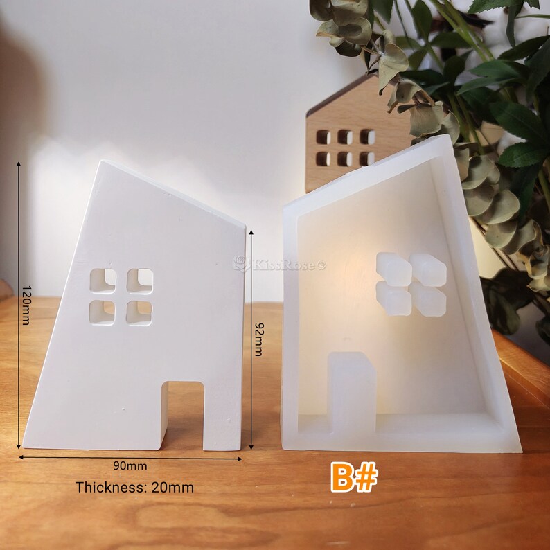 May include: Two white silicone moulds shaped like houses with windows and doors. The moulds are 90mm wide, 120mm tall, and 20mm thick. The mould on the right is labelled "B#"