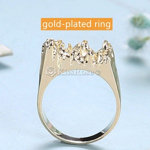 May include: Gold-plated ring with a textured mountain-like design. The ring is a statement piece with a unique and modern style.