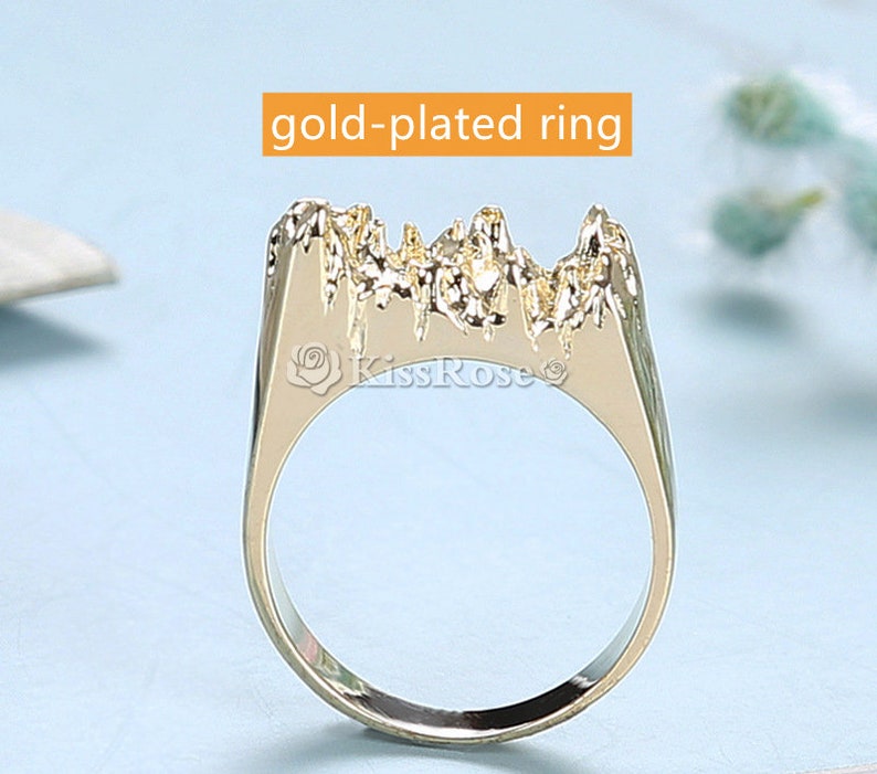 May include: Gold-plated ring with a textured mountain-like design. The ring is a statement piece with a unique and modern style.