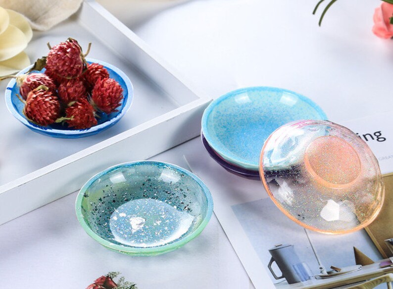 Op de afbeelding: Vier kleine, ronde, decoratieve schalen met een gespikkelde, iriserende afwerking. De schalen zijn in tinten blauw, groen en roze.