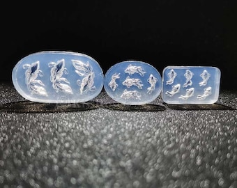 May include: Three clear silicone molds with raised fish designs. The molds are oval and rectangular in shape.