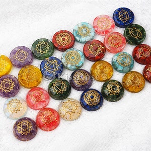 May include: Set of 20 chakra stones with gold symbols on a white background. Each stone is a different color and has a different symbol.