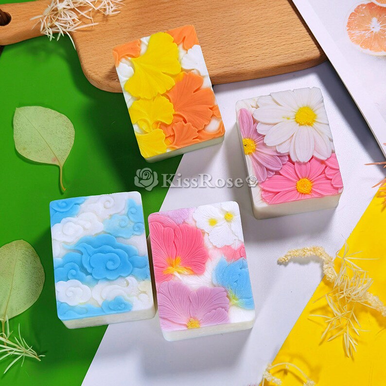 May include: Four rectangular bars of soap with different floral and geometric designs. The soaps are white with various colors, including blue, pink, orange, and yellow.