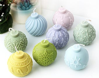 Puede incluir: Ocho velas decorativas con forma de bola de Navidad en varios colores y diseños. Las velas tienen forma de bola y presentan diferentes patrones, incluyendo copos de nieve, árboles y espirales.