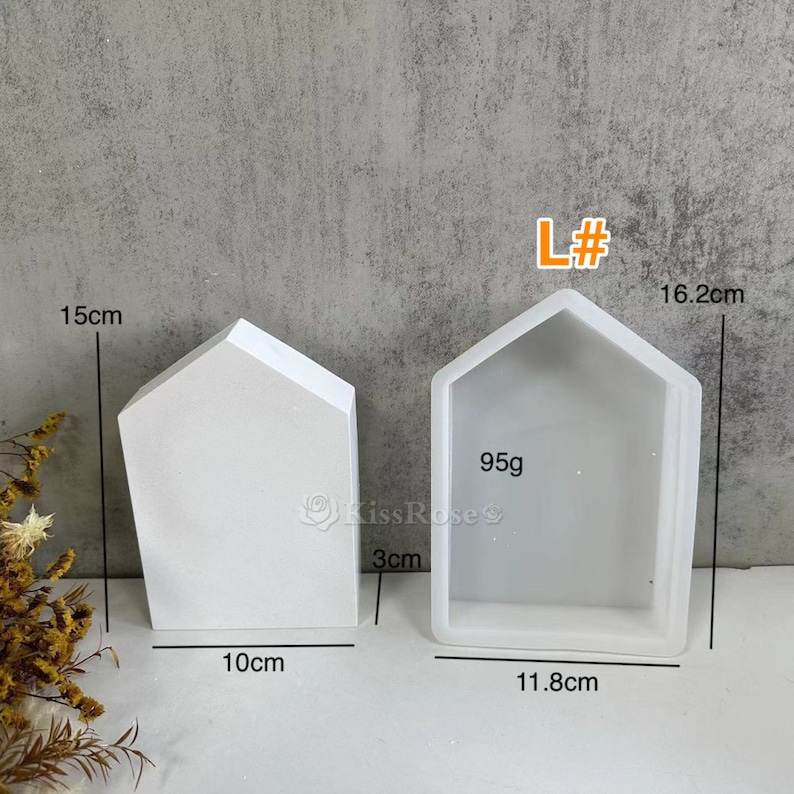 K&ouml;nnte beinhalten: Zwei wei&szlig;e hausf&ouml;rmige Silikonformen zum Basteln. Die gr&ouml;&szlig;ere Form ist 16,2 cm hoch, 11,8 cm breit und 3 cm tief. Die kleinere Form ist 15 cm hoch, 10 cm breit und 3 cm tief. Die Formen sind mit "L#" und "95g" gekennzeichnet.