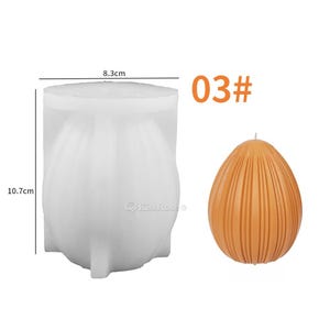 May include: A white silicone mold for making candles in the shape of an egg with vertical ridges. The mold is 8.3 cm wide and 10.7 cm tall. A finished candle is shown in orange with the same shape and ridges. The text "03#" is also shown in the image.