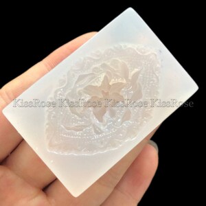 May include: A clear silicone mold with a raised design of a flower with intricate details. The mold is perfect for creating resin crafts.