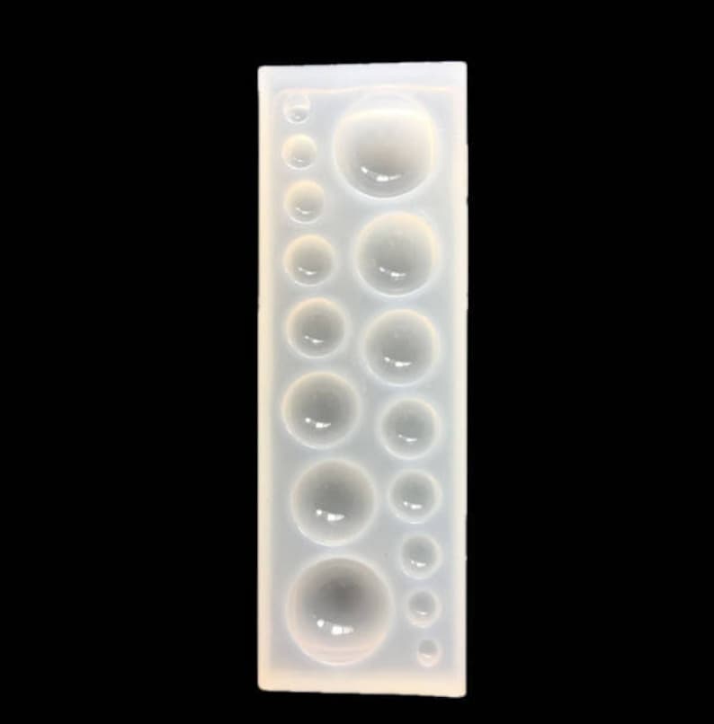 K&ouml;nnte beinhalten: Eine transparente Silikonform mit 12 runden Vertiefungen in verschiedenen Gr&ouml;&szlig;en. Die Form ist zum Erstellen von Harz-Cabochons gedacht.