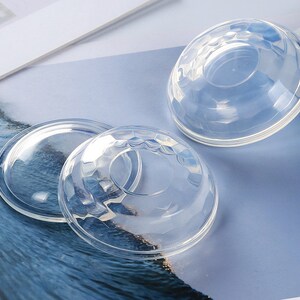 Op de afbeelding: Drie transparante plastic koepeldeksels voor containers. De deksels zijn glad en hebben een lichte kromming.