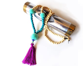 Boho necklace of wooden beads with pompons and pendant purple tassel. Completion of macramé.