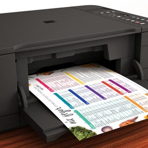 May include: A black all-in-one printer with a white sheet of paper coming out of the paper tray. The paper has a colorful chart with the text "My Recipes" and "Side Dish Ideas for Every Meal" printed on it.