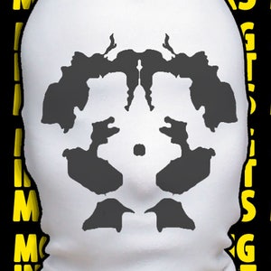 May include: A white balaclava with a gray inkblot design. The design is symmetrical and resembles a human face. The balaclava is a type of face mask that covers the head and neck.