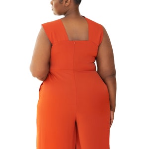 Model wearing Onika Orange Jumpsuit with asymmetrical neckline back view