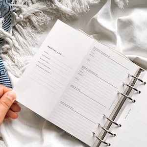 May include: A white medical log book with a black and white design. The book has a section for medical information, including name, birthdate, blood type, health provider, emergency contact, doctor's information, dentist information, medications, and medical history.