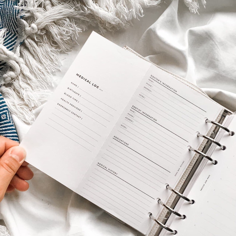 May include: A white medical log book with a black and white design. The book has a section for medical information, including name, birthdate, blood type, health provider, emergency contact, doctor's information, dentist information, medications, and medical history.