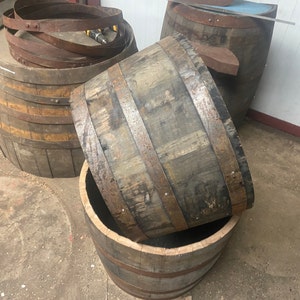 May include: Three wooden barrels, two are stacked on top of each other, and the third is lying on its side. The barrels are made of dark wood and have metal bands around them.