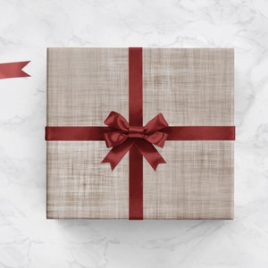 May include: A brown gift box with a red ribbon and bow. The box is on a white marble surface.