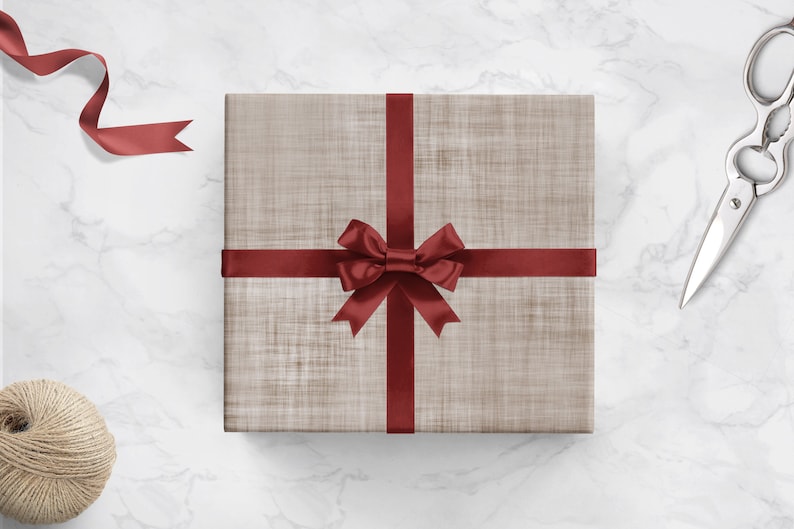 May include: A brown gift box with a red ribbon and bow. The box is on a white marble surface.