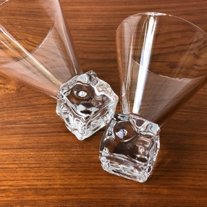 May include: Two clear glass martini glasses with a unique ice cube base. The glasses are on a wooden surface.