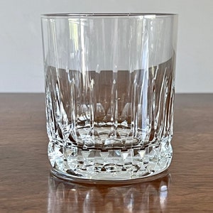 Puede incluir: Un vaso de vidrio transparente con un dise&ntilde;o de vidrio cortado. El vaso tiene una base ancha y lados rectos.