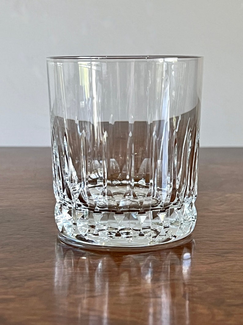 Puede incluir: Un vaso de vidrio transparente con un dise&ntilde;o de vidrio cortado. El vaso tiene una base ancha y lados rectos.