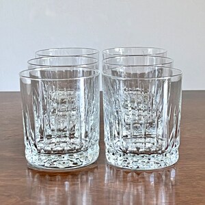 Puede incluir: Juego de seis vasos de cristal transparente con un patr&oacute;n texturizado en forma de diamante. Los vasos est&aacute;n vac&iacute;os y se encuentran sobre una superficie de madera.