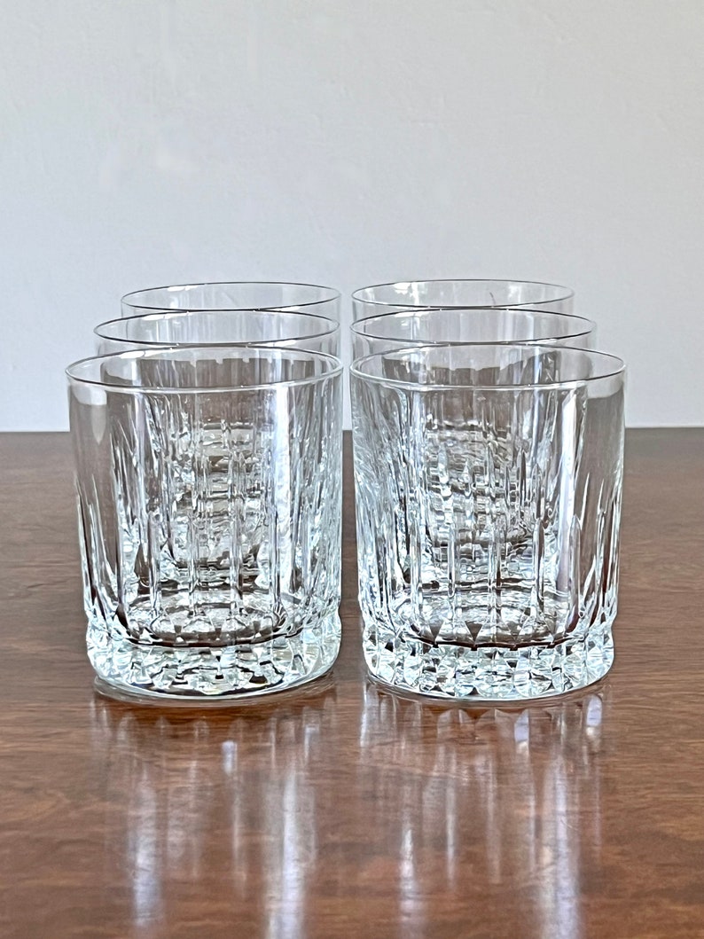 Puede incluir: Juego de seis vasos de cristal transparente con un patr&oacute;n texturizado en forma de diamante. Los vasos est&aacute;n vac&iacute;os y se encuentran sobre una superficie de madera.