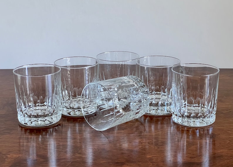 Puede incluir: Seis vasos transparentes de vidrio con un dise&ntilde;o texturizado y acanalado. Los vasos est&aacute;n dispuestos en semic&iacute;rculo sobre una superficie de madera.