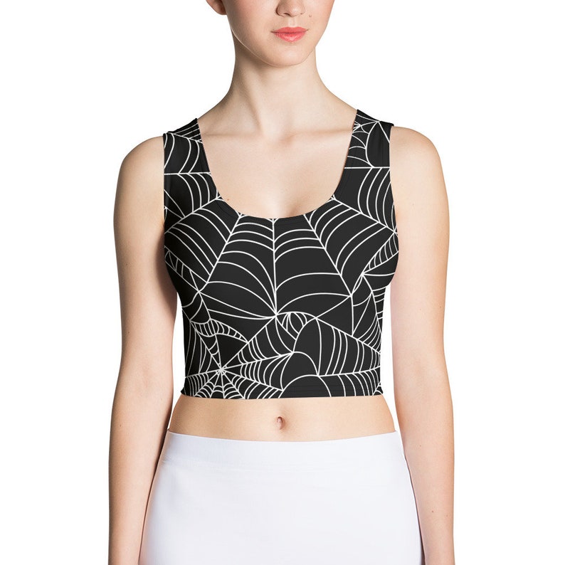 May include: Black crop top with a white spiderweb pattern. The top has a scoop neck and sleeveless design.