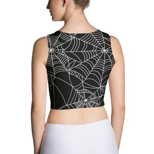 May include: Black sleeveless crop top with a white spiderweb pattern.