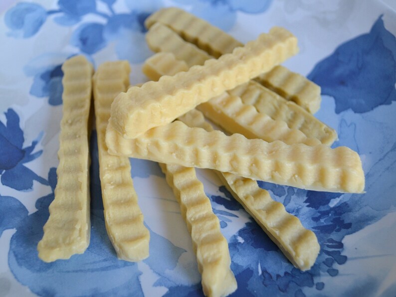K&ouml;nnte beinhalten: Nahaufnahme eines Tellers mit hellbraunen, gewellten, knusprigen, frittierten Snacks. Die Snacks sind auf einem wei&szlig;en Teller mit blauem Blumendesign gestapelt.