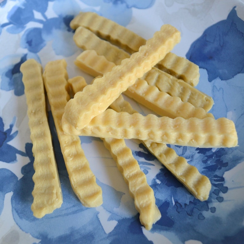 K&ouml;nnte beinhalten: Nahaufnahme eines Tellers mit acht hellbraunen, gewellten, knusprigen, frittierten Snacks. Die Snacks sind auf einem blau-wei&szlig; gemusterten Teller gestapelt.