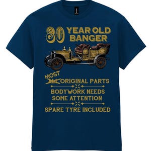 Op de afbeelding: Een marineblauw t-shirt met een vintage autografiek en de tekst "80 YEAR OLD BANGER MOST ORIGINAL PARTS BODYWORK NEEDS SOME ATTENTION SPARE TYRE INCLUDED".