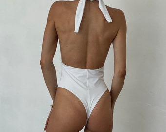 Stringbadpak uit één stuk: hoog uitgesneden, diepe v-hals, monokini zonder rug. Aangepaste pasvorm.