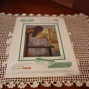 May include: A packaged cross-stitch kit featuring a woman seated in a chair, with the text "Muchacha de espaldas." The kit measures approximately 15.7 x 21.6 inches. The packaging includes the brand "Eder Kits" and the reference number VA-98-009.