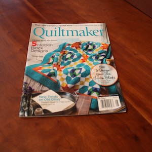 May include: Quiltmaker magazine cover featuring a colorful quilt with a turquoise, yellow, red, and white pattern. The cover text reads "Start Your Christmas Quilts Now!" and "5 Hidden Block Designs".