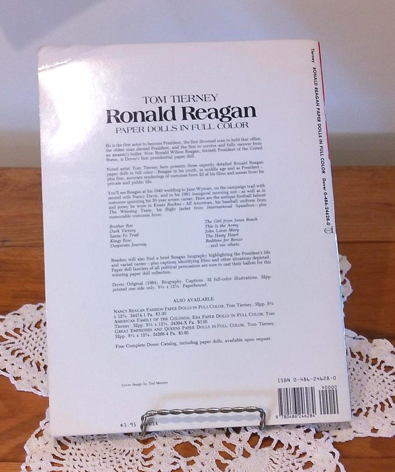 May include: The back cover of a paperback book titled "Ronald Reagan Paper Dolls in Full Color" by Tom Tierney. The book features a biography and paper doll illustrations. The book measures 9.25 x 12 inches.