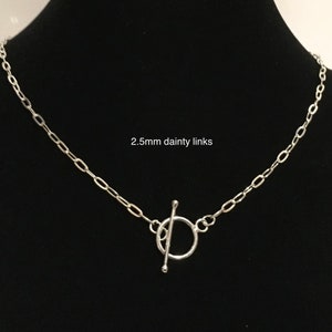 May include: A silver necklace with a toggle clasp. The chain is made of 2.5mm dainty links.